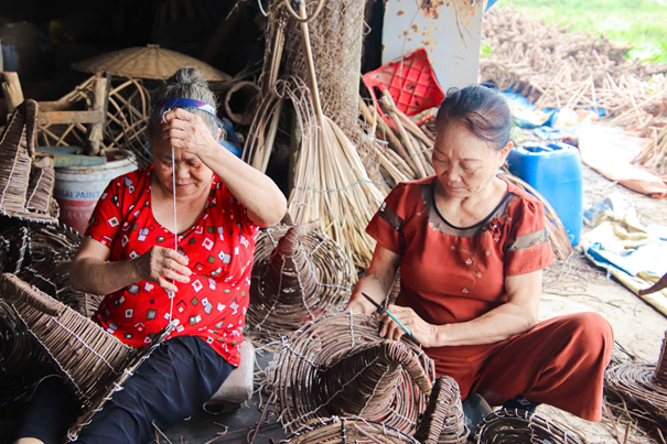 Đội ngũ thợ lành nghề lớn tuổi quây quần đan lát, tạo nên bầu không khí làm việc ấm cúng như một gia đình tại xưởng Giang Huyền